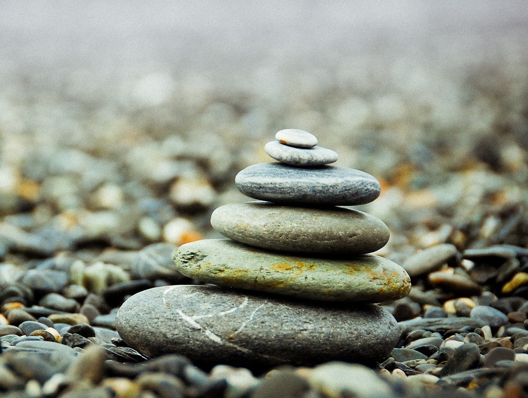 Več ravnih kamnov je zloženih en na drugega v obliki stolpa na prodnati podlagi