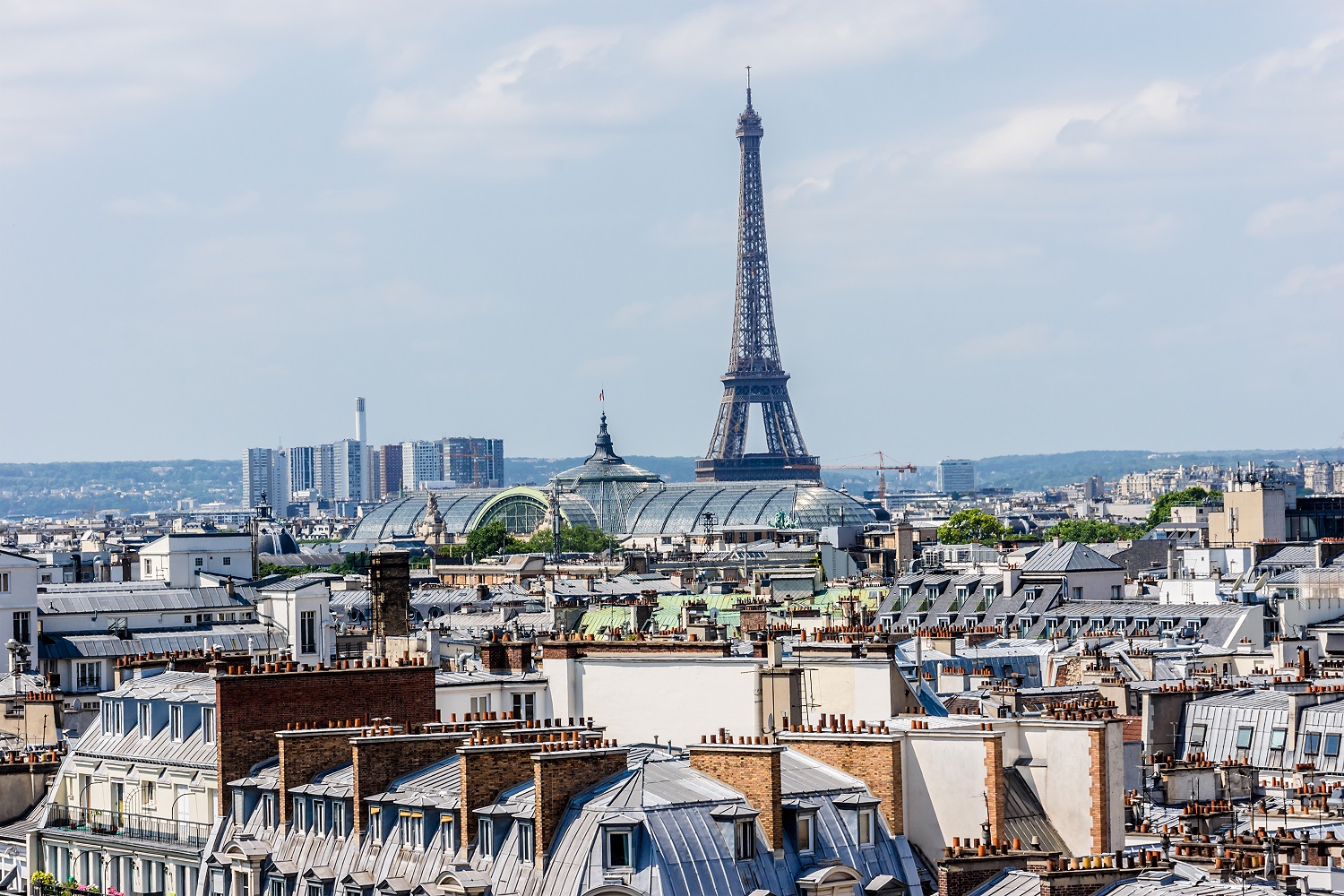 Pogled na pariške strehe z Eifflovim stolpom v ozadju in jasno modrim nebom nad mestom
